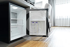 Black mini small fridge refrigerator under the frame wooden counter in hotel resort bedroom