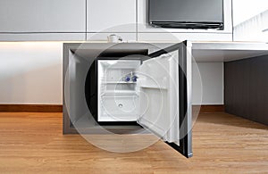 Black mini small fridge refrigerator under the frame wooden counter in hotel resort bedroom