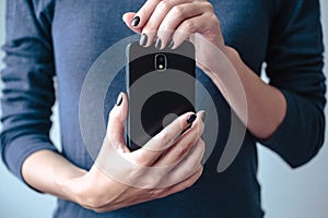 Black mobie smart phone in woman/s hands with perfect dark violet manicure
