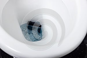 Black mobile phone falling into toilet water