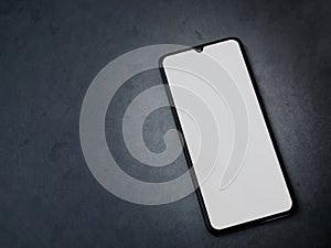 Black mobile smartphone mockup lies on the surface with a blank screen isolated on a dark marble stone background