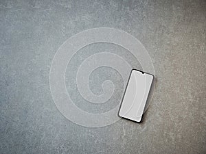 Black mobile smartphone mockup lies on the surface with a blank screen isolated on a porcelain granite ceramic stone background