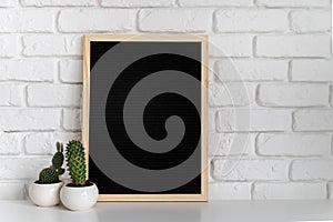 Black mock up felt letter board with small succulents on white brick background