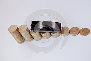 A black model of a car with coins in the form of a histogram on a white background. Concept of lending, savings, insurance
