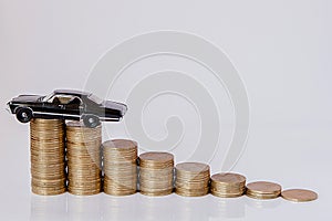 A black model of a car with coins in the form of a histogram on a white background. Concept of lending, savings, insurance