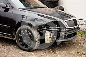 Black modern car damaged in a traffic accident without headlamps and bumper