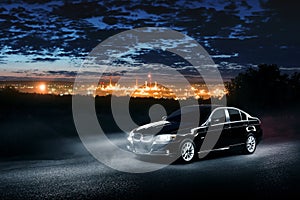 Black modern car standing in mist forest at night