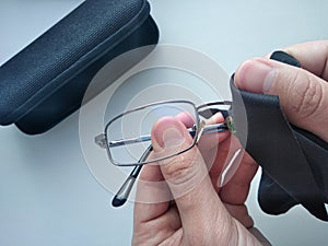 Black modern eyeglasses with case.Man wipes with a cloth the glass from contaminants.Cleaning glasses medical glasses.