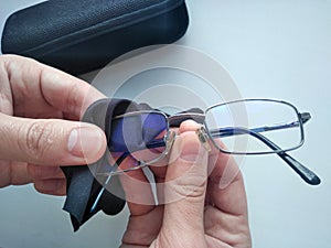 Black modern eyeglasses with case.Man wipes with a cloth the glass from contaminants.Cleaning glasses medical glasses.