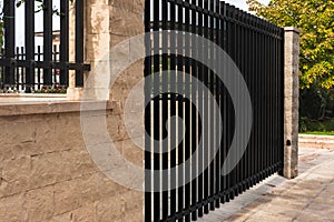 Black modern gate. Black metal garden entrance gates set in brick fence