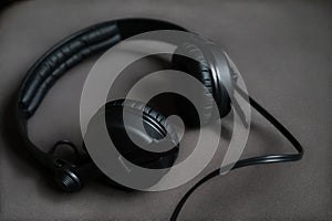 Black, modern headphones with cord on a clean, grey background