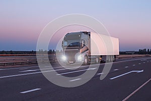 A black modern truck wagon transports cargo in a trailer refrigerator at night. Concept logistics and online stock exchange for