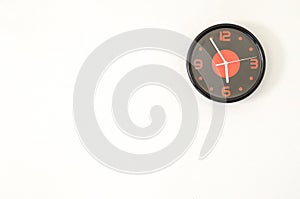 Black modern wall clock on white concrete wall with palce for te