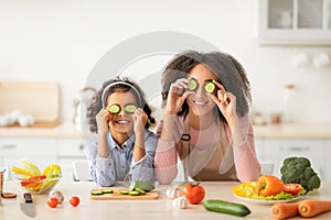 Black mom and daughter playing with food in the kitchen