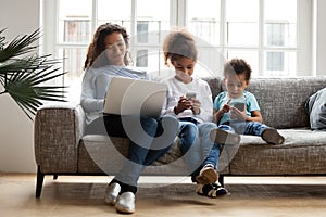 Black mom and kids using laptop phones addicted to devices
