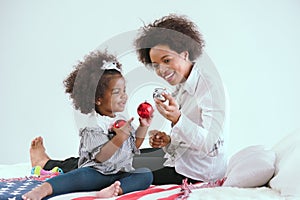 Black mother and daughter playfully play with toys in the bedroom of the house