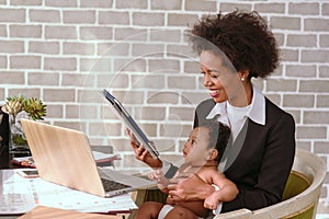 Black mother is working on the phone and raising her children together in the house.