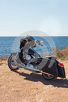 Black motorcycle on beautiful seacoast and blue sky. Prairie, steppe, summer.