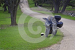 A black motorcycle with luggage parked on a rural Texas Hill Country road