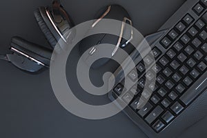 Black mouse, the keyboard, the headphones are isolated on a dark background, the top view. Flat lay gamer background