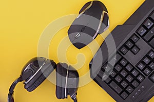 Black mouse, the keyboard, the headphones are isolated on a yellow background, the top view. gamer background