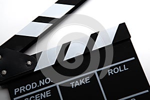 Black movie clapper with white inscriptions on a white table