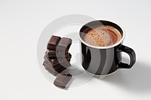 Black mug with hot chocolate served with chunks of dark chocolate