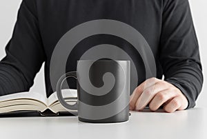 Black mug mockup with man reading a book