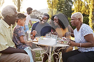 Black multi generation family eating at a table in garden