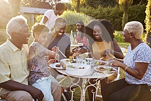 Black multi generation family eating at a table in garden