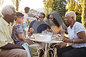 Nero Di più generazioni famiglia mangiare sul tavolo giardino 