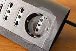 Black multi-socket on wooden table closeup