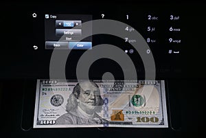 Black multifunction printer with touch screen display makes copy of 100 dollar bill in the dark. Money machine.