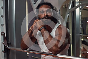 a black muscular man in a narrow white T-shirt stands at the gym