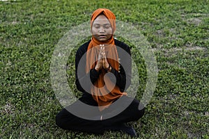 Black muslim woman meditating yoga and pray on grass. Lifestyle of african female.