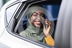 Black muslim woman traveling on car back seat and talking on cellphone