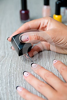 Black nail polish being applied to hand with tools for manicure on background. Beautiful manicure process. Close up.
