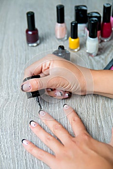 Black nail polish being applied to hand with tools for manicure on background. Beautiful process. Close up.