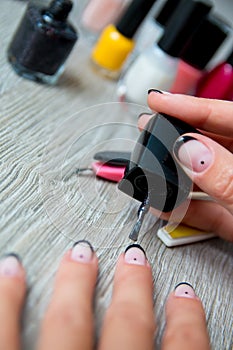 Black nail polish being applied to hand with tools for manicure on background. Beautiful process. Close up.