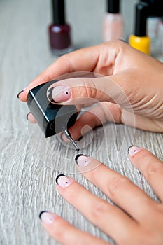 Black nail polish being applied to hand with tools for manicure on background. Beautiful process. Close up.
