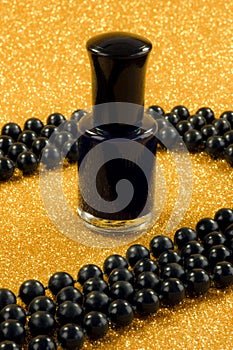 Black nail varnish and beads on a gold surface.