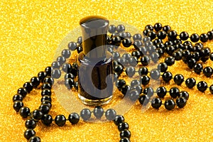 Black nail varnish and beads on a golden background.