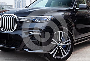 Black new BMW X7 xDrive40i 2019 year front led headlight, turned wheel and bumper view with light gray interior on parking in the