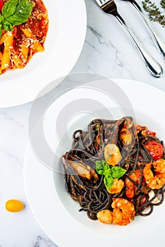 black noodles with mussels, shrimp, tomatoes and herbs top view