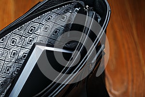 Black notebook peeking out of the pocket of a black leather bag close-up, macro Handmade, natural materials