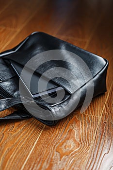 Black notebook peeking out of the pocket of a black leather bag close-up, macro Handmade, natural materials