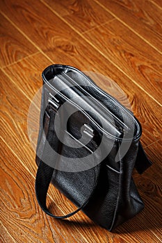 Black notebook peeking out of the pocket of a black leather bag close-up, macro Handmade, natural materials