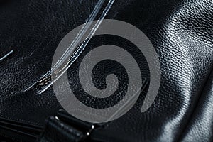 Black notebook peeking out of the pocket of a black leather bag close-up, macro Handmade, natural materials