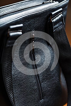 Black notebook peeking out of the pocket of a black leather bag close-up, macro Handmade, natural materials