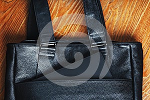 Black notebook peeking out of the pocket of a black leather bag close-up, macro Handmade, natural materials